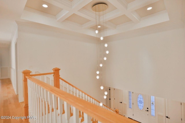 hall with a towering ceiling, coffered ceiling, beam ceiling, and an upstairs landing