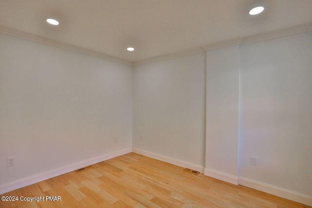 empty room featuring crown molding, recessed lighting, light wood-type flooring, and baseboards