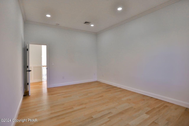 empty room with light wood finished floors, ornamental molding, visible vents, and baseboards