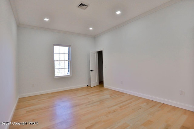 empty room featuring light wood-style floors, visible vents, and baseboards