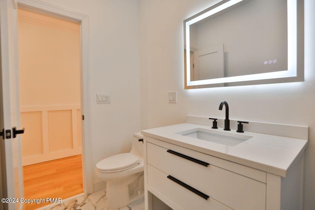 half bathroom featuring marble finish floor, vanity, and toilet