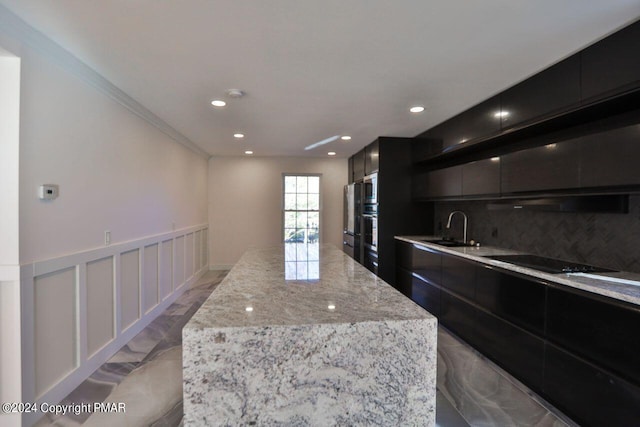 kitchen with black electric cooktop, a sink, wainscoting, a center island, and modern cabinets