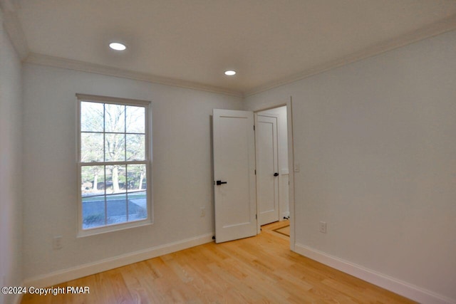 empty room featuring baseboards, recessed lighting, light wood-type flooring, and crown molding