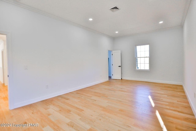 unfurnished room featuring light wood-style floors, baseboards, visible vents, and ornamental molding