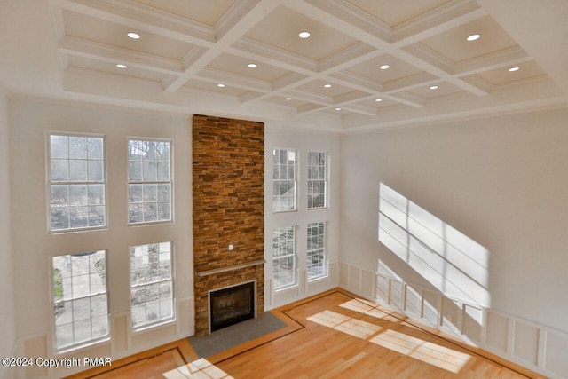 unfurnished living room featuring a high ceiling, coffered ceiling, wood finished floors, ornamental molding, and beamed ceiling