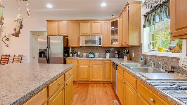 169 Roberts Rd, Starlight, PA 18461 - kitchen with appliances with stainless steel finishes, light wood-style flooring, glass insert cabinets, decorative backsplash, and light countertops