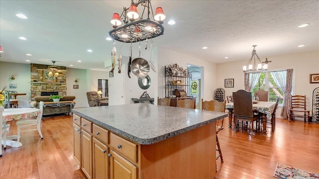 169 Roberts Rd, Starlight, PA 18461 - kitchen with a chandelier, a kitchen island, dark countertops, light wood-style floors, and a fireplace