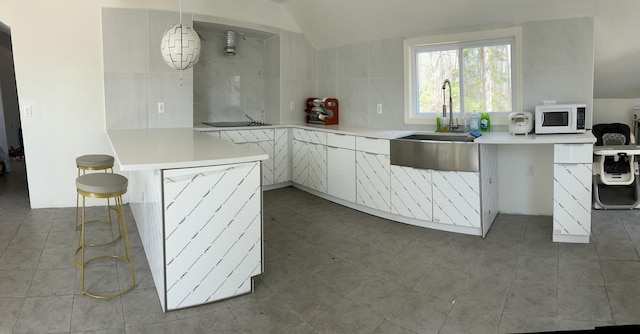108 Devils Hole Rd, Cresco, PA 18326 - kitchen featuring a sink, white microwave, white cabinetry, light countertops, and a breakfast bar