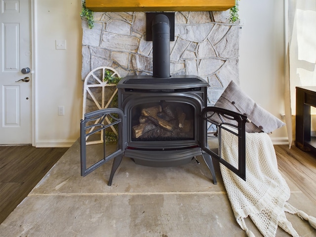 interior details featuring wood finished floors, a wood stove, and baseboards