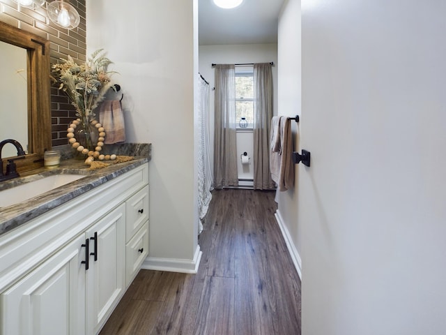 bathroom featuring curtained shower, vanity, baseboards, and wood finished floors