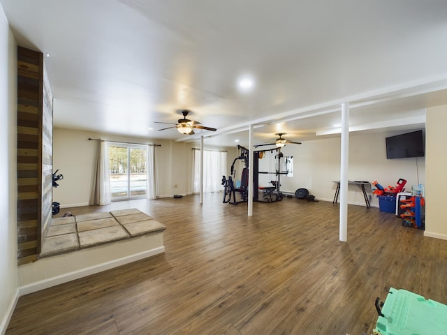 exercise room with wood finished floors, a ceiling fan, and baseboards