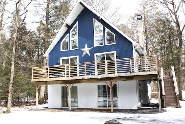 snow covered property with stairway, a chimney, and a wooden deck