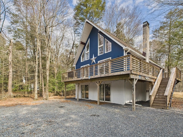 view of front of home featuring stairway, a wooden deck, and a chimney