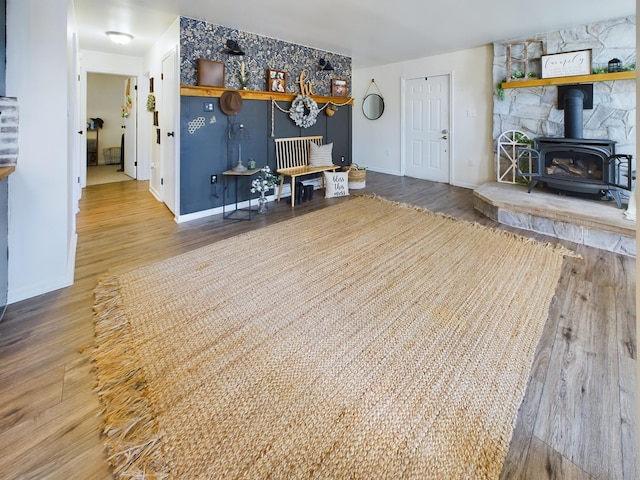 living area with wood finished floors, a wood stove, and baseboards