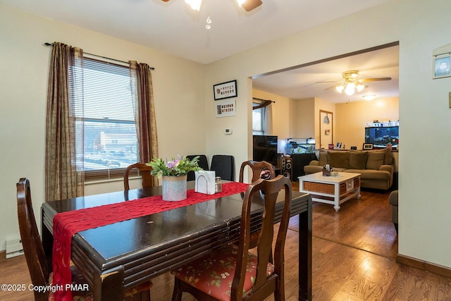 dining space featuring dark hardwood / wood-style flooring, ceiling fan, and a baseboard heating unit