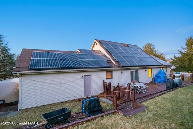 rear view of house with a lawn, solar panels, and a wooden deck