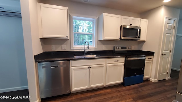 kitchen with dark countertops, white cabinets, stainless steel appliances, and a sink