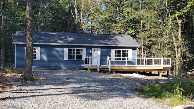 view of front facade featuring a deck, driveway, and a wooded view