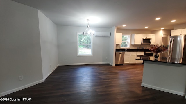 kitchen featuring dark countertops, a wall mounted AC, appliances with stainless steel finishes, dark wood-type flooring, and a sink