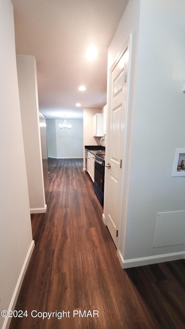 hallway featuring baseboards, dark wood finished floors, and a sink