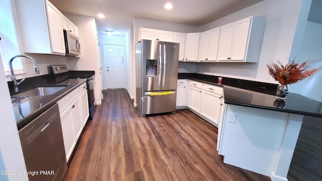 kitchen featuring stainless steel appliances, dark wood-type flooring, a sink, and white cabinetry