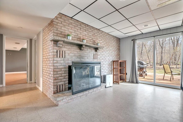 unfurnished living room with a fireplace, baseboards, and a paneled ceiling