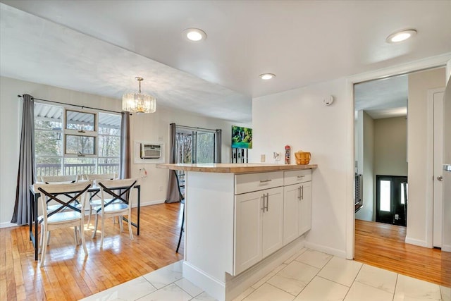 kitchen featuring a chandelier, baseboards, white cabinets, pendant lighting, and recessed lighting