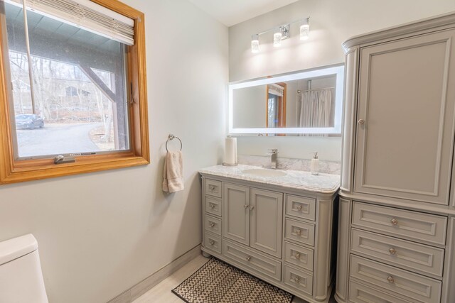 bathroom with toilet, baseboards, and vanity