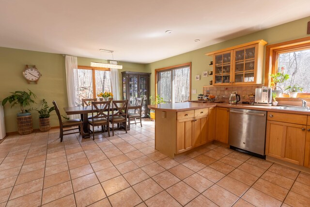 kitchen featuring a peninsula, a sink, light countertops, dishwasher, and glass insert cabinets