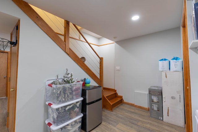 interior space featuring recessed lighting, wood finished floors, baseboards, stairway, and freestanding refrigerator