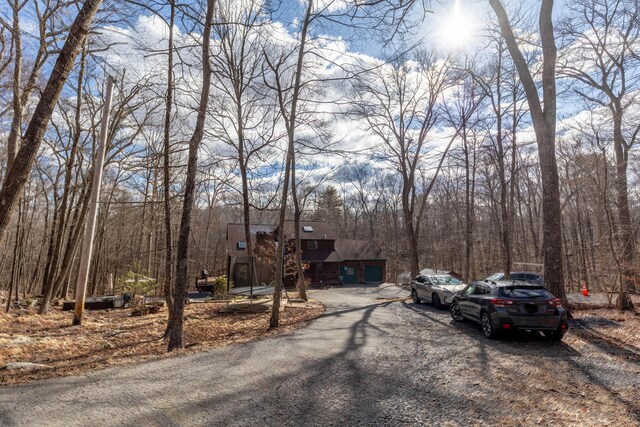 view of street with aphalt driveway and a wooded view