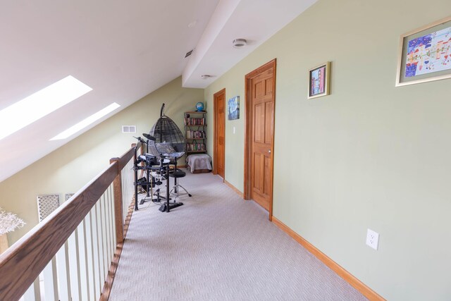 hallway with light carpet, lofted ceiling with skylight, baseboards, and visible vents