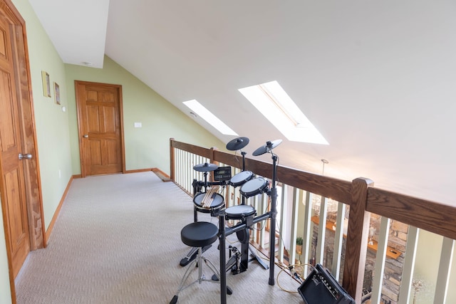 interior space featuring carpet floors, vaulted ceiling with skylight, and baseboards