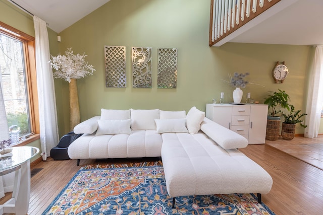 living room with high vaulted ceiling, wood finished floors, and visible vents