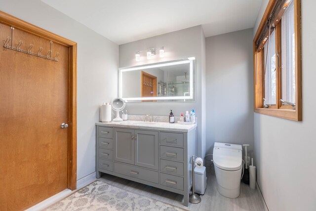 full bathroom with toilet, baseboards, and vanity