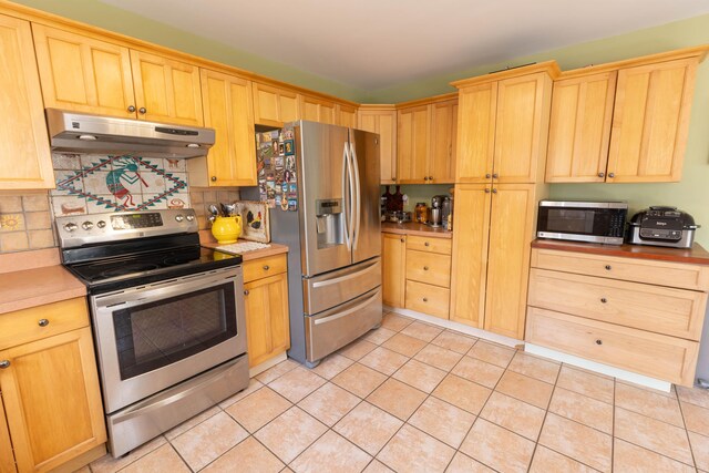 kitchen featuring light brown cabinets, stainless steel appliances, light countertops, and under cabinet range hood