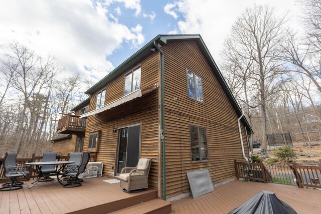 rear view of house featuring outdoor dining area and a wooden deck