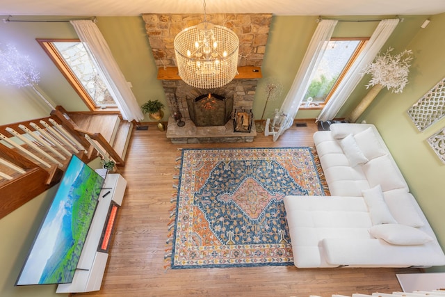 living room featuring an inviting chandelier, a fireplace, visible vents, and wood finished floors