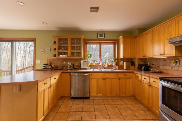 kitchen with visible vents, decorative backsplash, appliances with stainless steel finishes, a sink, and a peninsula