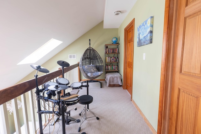 interior space with carpet floors, lofted ceiling with skylight, visible vents, and baseboards