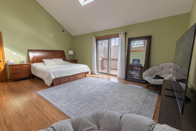 bedroom featuring high vaulted ceiling, a skylight, visible vents, access to outside, and wood-type flooring