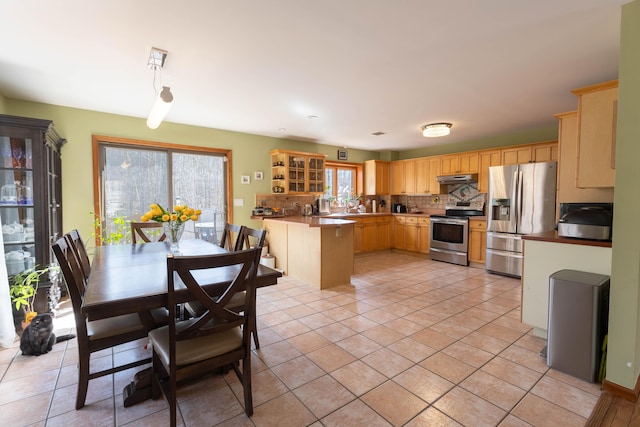 kitchen featuring under cabinet range hood, stainless steel appliances, decorative backsplash, and light tile patterned flooring