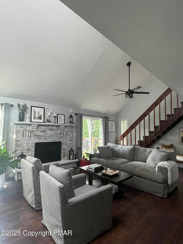 living room featuring vaulted ceiling, a stone fireplace, dark hardwood / wood-style floors, and ceiling fan