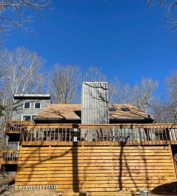 exterior space with a shingled roof and a deck