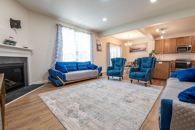 320 Bendelow Ln, Northampton, PA 18067 - living room featuring light wood-style floors, a chandelier, a glass covered fireplace, recessed lighting, and beamed ceiling