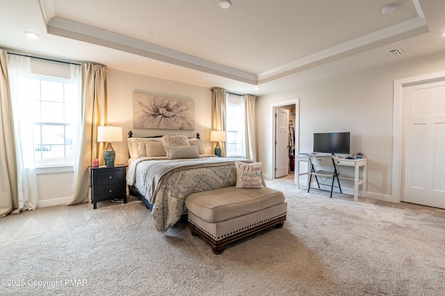 bedroom with light carpet and a tray ceiling