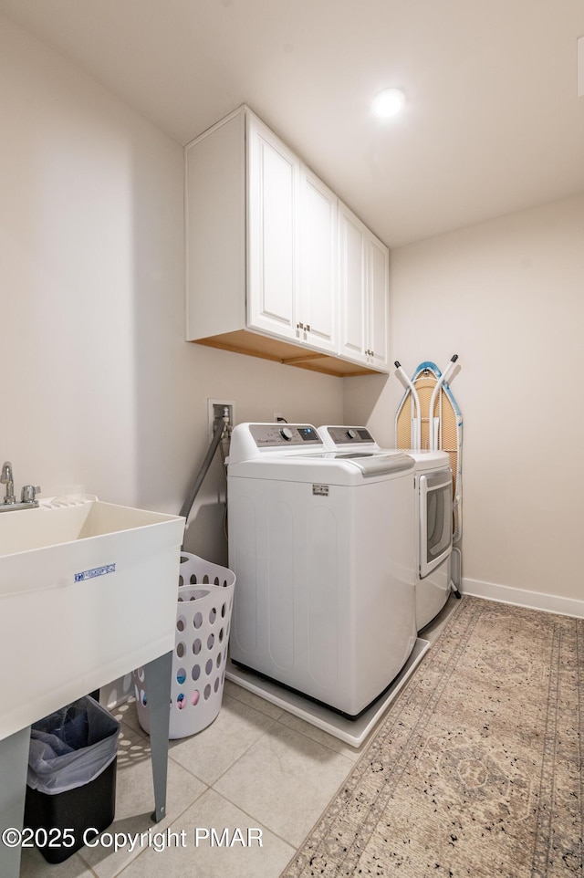 laundry area with cabinets, washer and dryer, and light tile patterned floors