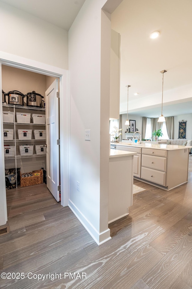 interior space with decorative light fixtures, light hardwood / wood-style floors, and kitchen peninsula