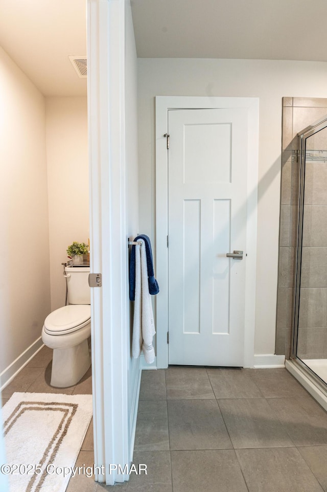 bathroom with a shower with door, tile patterned floors, and toilet