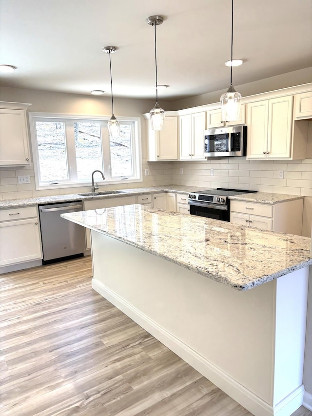 247 Sandlewood Dr, East Stroudsburg, PA 18301 - kitchen with appliances with stainless steel finishes, a sink, light wood finished floors, decorative backsplash, and a kitchen island
